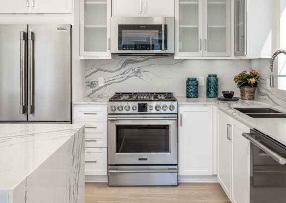 a white kitchen with stainless steel appliances and white cabinets