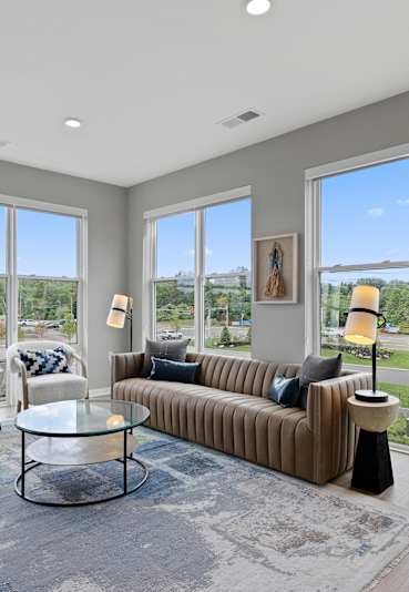 a living room with couches and chairs and large windows