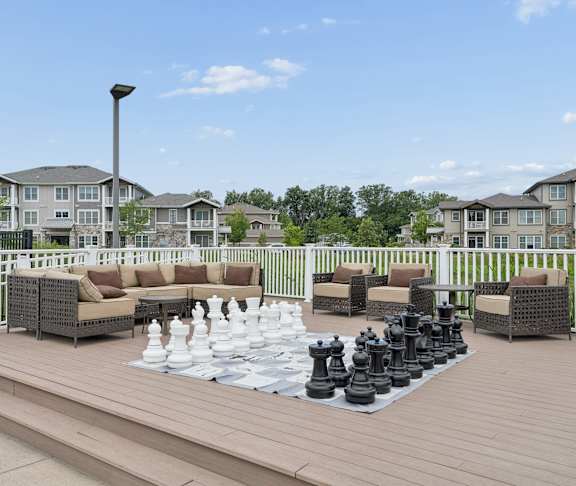 A giant chess set is set up on a wooden deck.