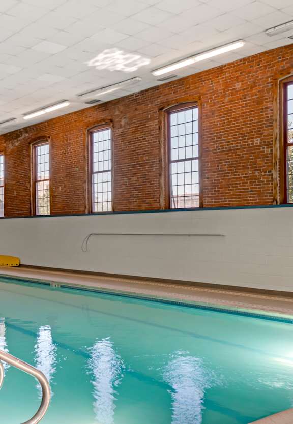 a brick building with a large pool in front of it at Bigelow Commons, Connecticut, 06082
