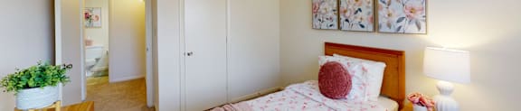 A bedroom with a pink bedspread and a wooden dresser.