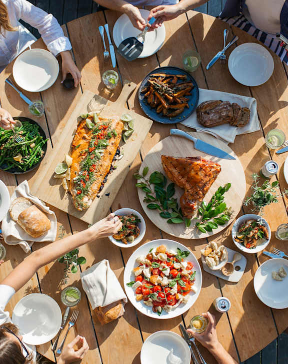 A group of people are sitting around a table with plates of food.