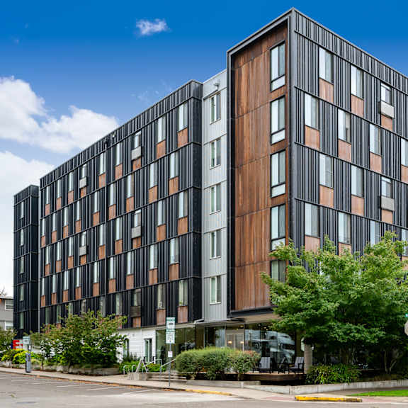 A modern multi-story building with a combination of black and brown panels.
