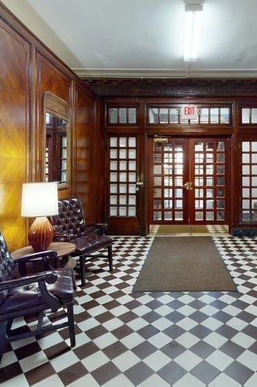 A hallway with a checkered floor and wooden doors.