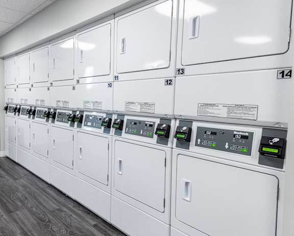 a row of washers and dryers in a utility room