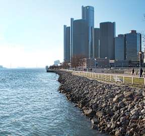 A city skyline is seen from a waterfront walkway.