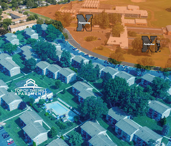 An aerial view of a large apartment complex with a parking lot in front.