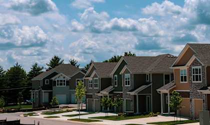 a row of houses in front of a blue cloudy sky