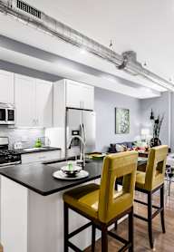 A kitchen with black cabinets and a white door.