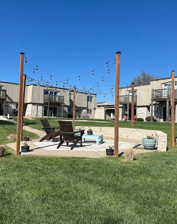 Outdoor seating area with table and chairs on a landscaped lawn at Park 25 Apartments.