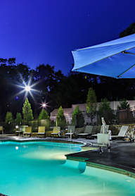 a swimming pool with chairs and umbrellas and trees