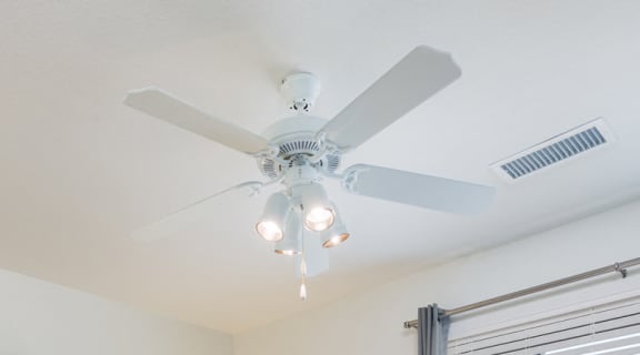 Ceiling fan, lamp and cozy bed at Arterra Place Apartments, Aurora, 80017