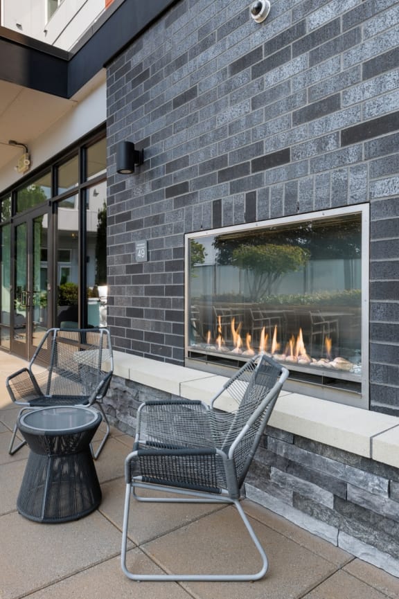a patio with couches tables and chairs and a building in the background at Wilcox, Seattle, Washington, 98107