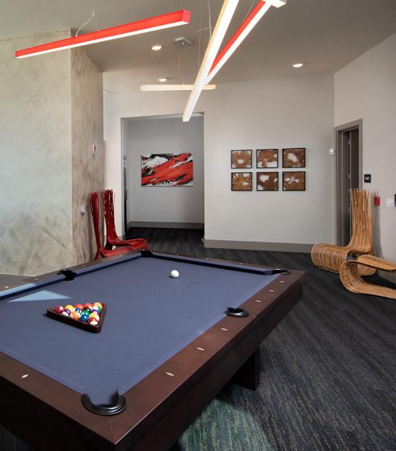 A pool table in a room with a red wall and a window.