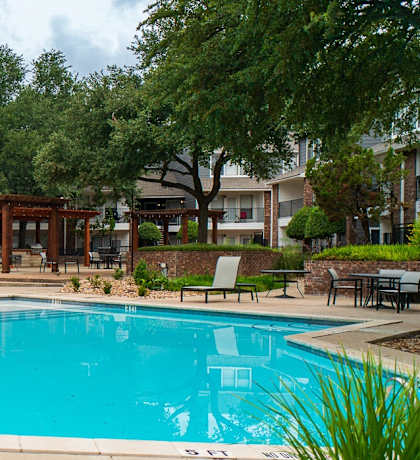 a swimming pool in courtyard with rocks and a wood fence