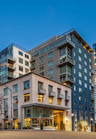 A modern multi-story building with a red car parked in front.