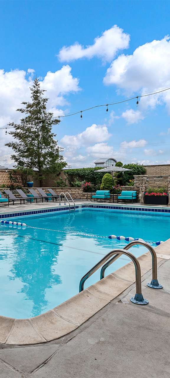 A large outdoor swimming pool with blue water and lounge chairs.