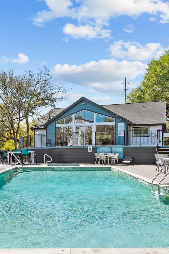 a swimming pool with orange chairs and a building in the background