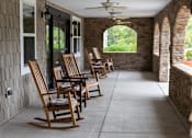 Thumbnail 1 of 6 - A row of wooden rocking chairs are lined up on a porch.