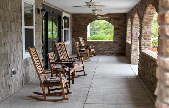 A row of wooden rocking chairs are lined up on a porch.