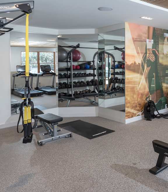 A gym with a variety of equipment including weights and a rowing machine.