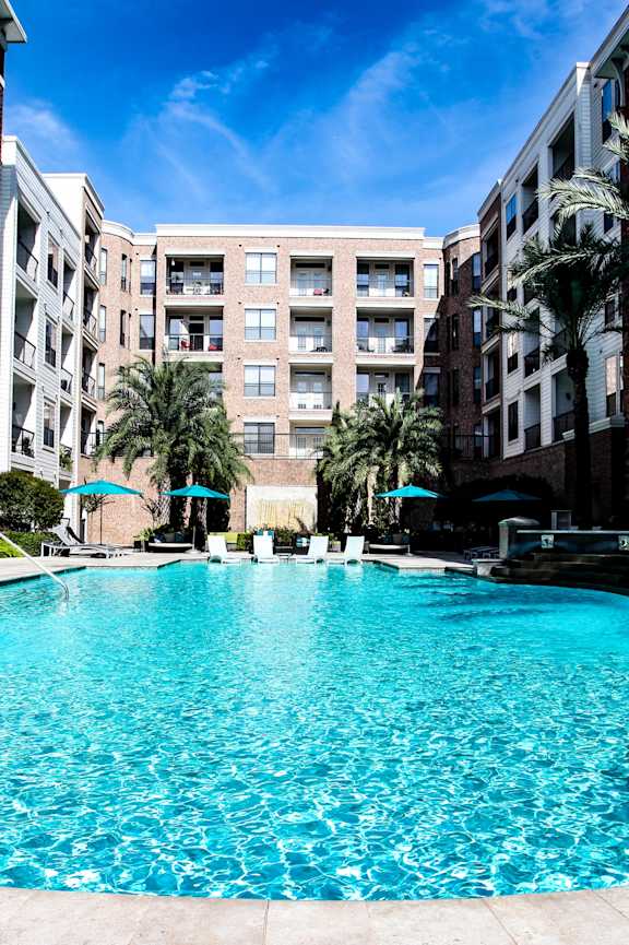 A swimming pool surrounded by buildings and palm trees.