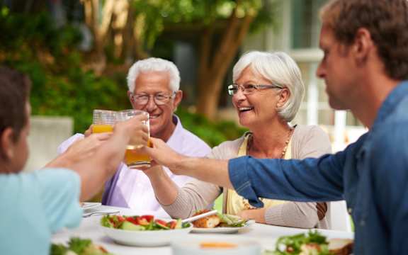 A family toasting with drinks at a dinner table.
