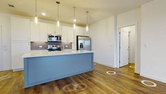 A kitchen area with a blue island and white cabinets.