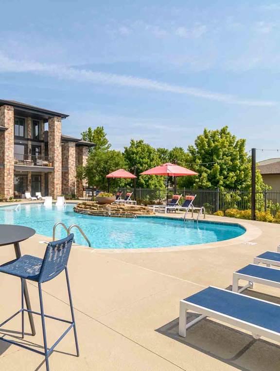 a swimming pool with a waterfall in front of a house