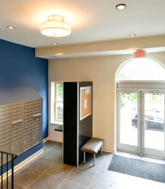 a hallway with blue walls and a staircase with a chair and lockers