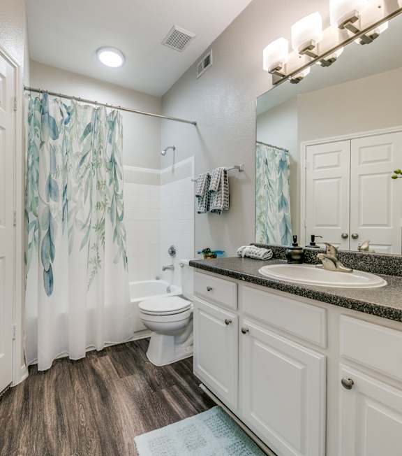 A white bathroom with a wooden floor and a white toilet.