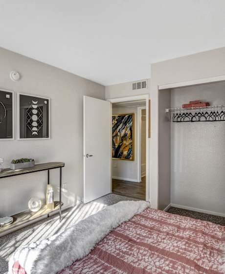 A bedroom with a bed, a shelf, and a doorway leading to another room at Parkway at Silverado Ranch, Las Vegas, NV.