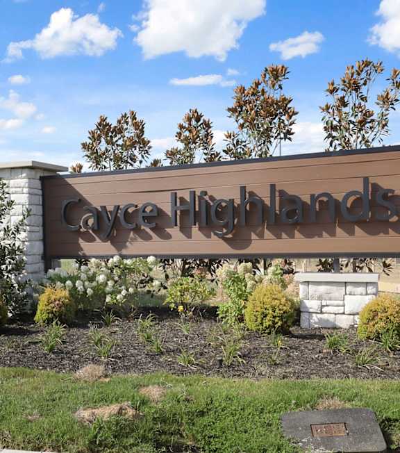 A sign that says "Cayce Highlands" is in front of a grassy area.