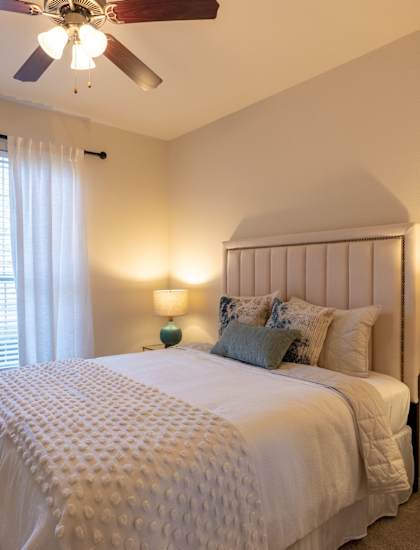 a bedroom with a large bed and a ceiling fan at The Park at Monterey Oaks, Austin, TX