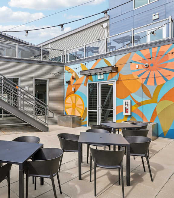 A patio with two chairs and a couch overlooking a city skyline.