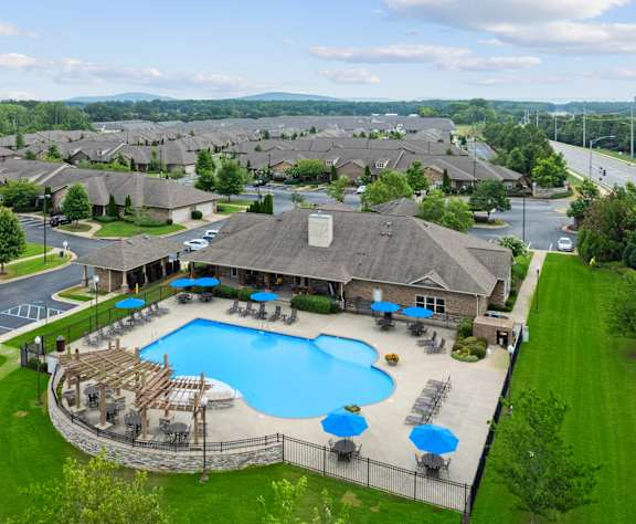 A large swimming pool surrounded by a fence and lounge chairs. at The Villas at Nature Walk, Huntsville, Alabama