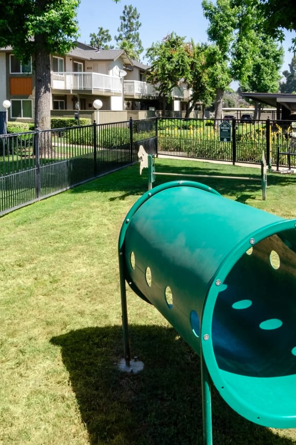 a green seesaw in a park next to a fence at Aspire Redlands, California