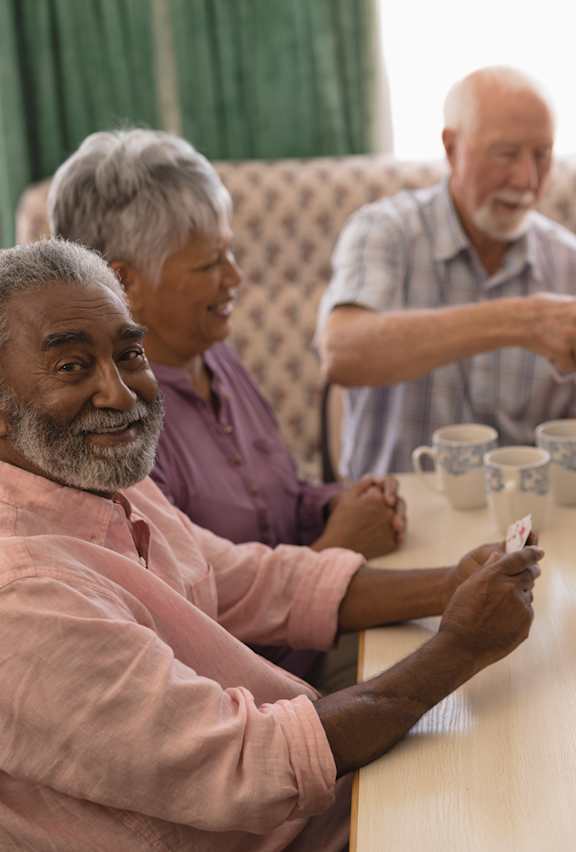 A group of elderly people are sitting around a table playing a card game.