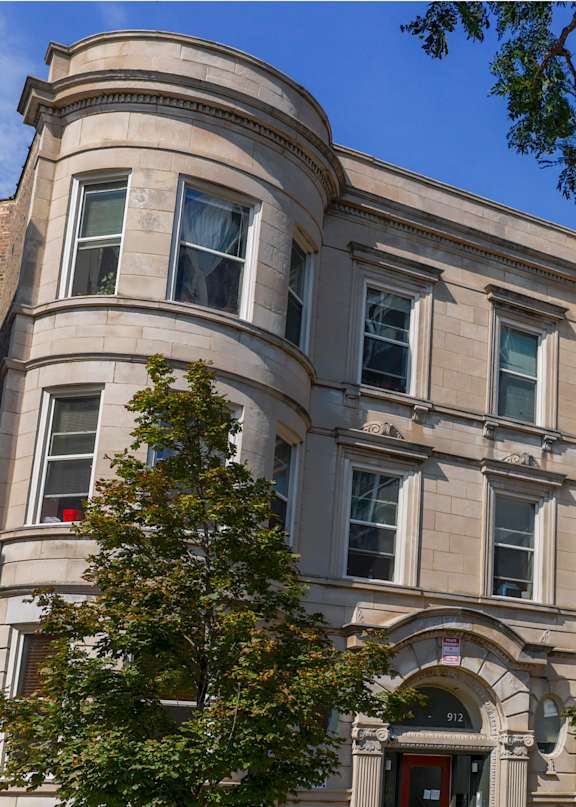 A large, old building with many windows and a flag on the front.