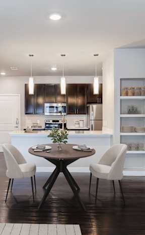A modern kitchen with a dining table set for two.