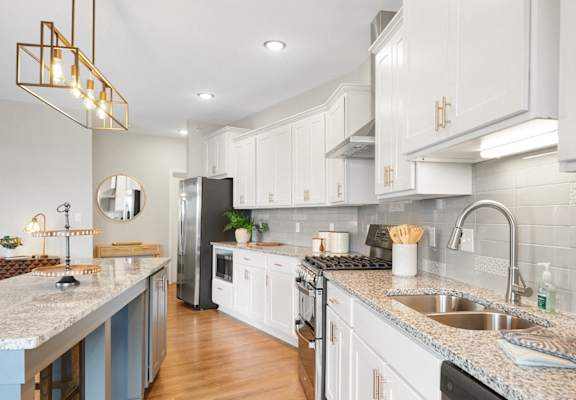 a large kitchen with marble counter tops and white cabinets