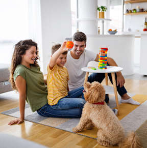 A family playing with a dog and building a tower with blocks.