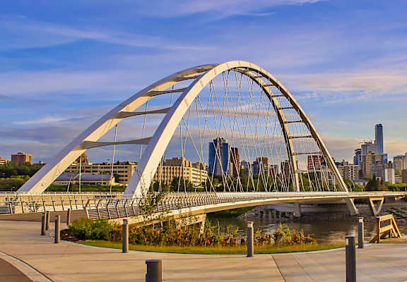 A modern bridge spans a river in a city.