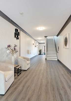 a long hallway with white walls and chairs and a staircase at The Franklin at Hillsborough Apartments, New Jersey