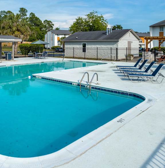 A large swimming pool with lounge chairs and a diving board.