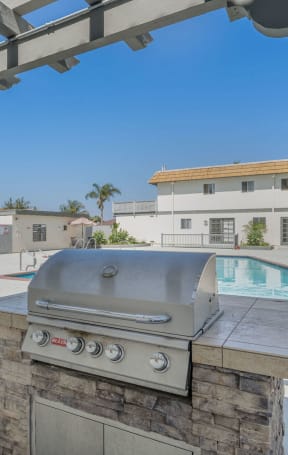 a backyard with a grill and a pool with buildings in the background at Ocean Villas, Oxnard