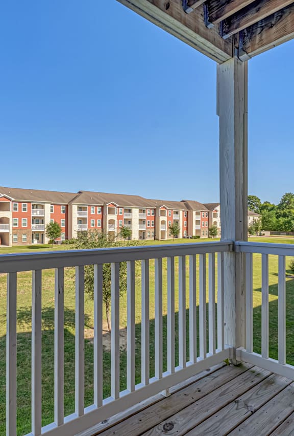 A view from a balcony overlooking a grassy area and apartment buildings.