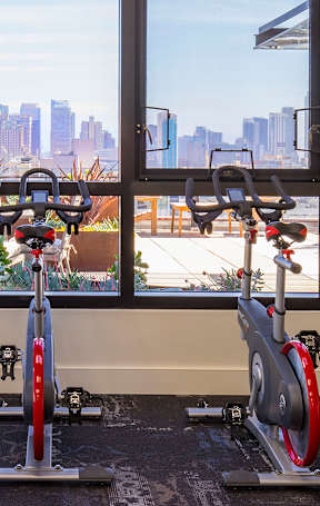 A gym with exercise bikes and a view of the city.