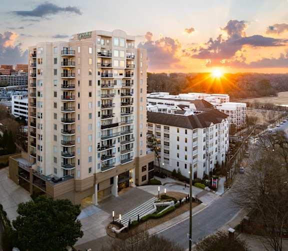 A tall apartment building with a sunset in the background.