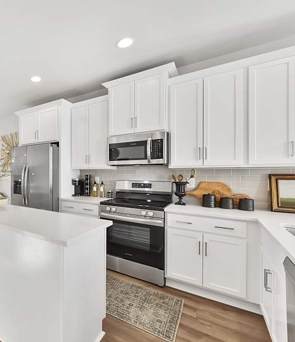 A modern kitchen with white cabinets and stainless steel appliances.
